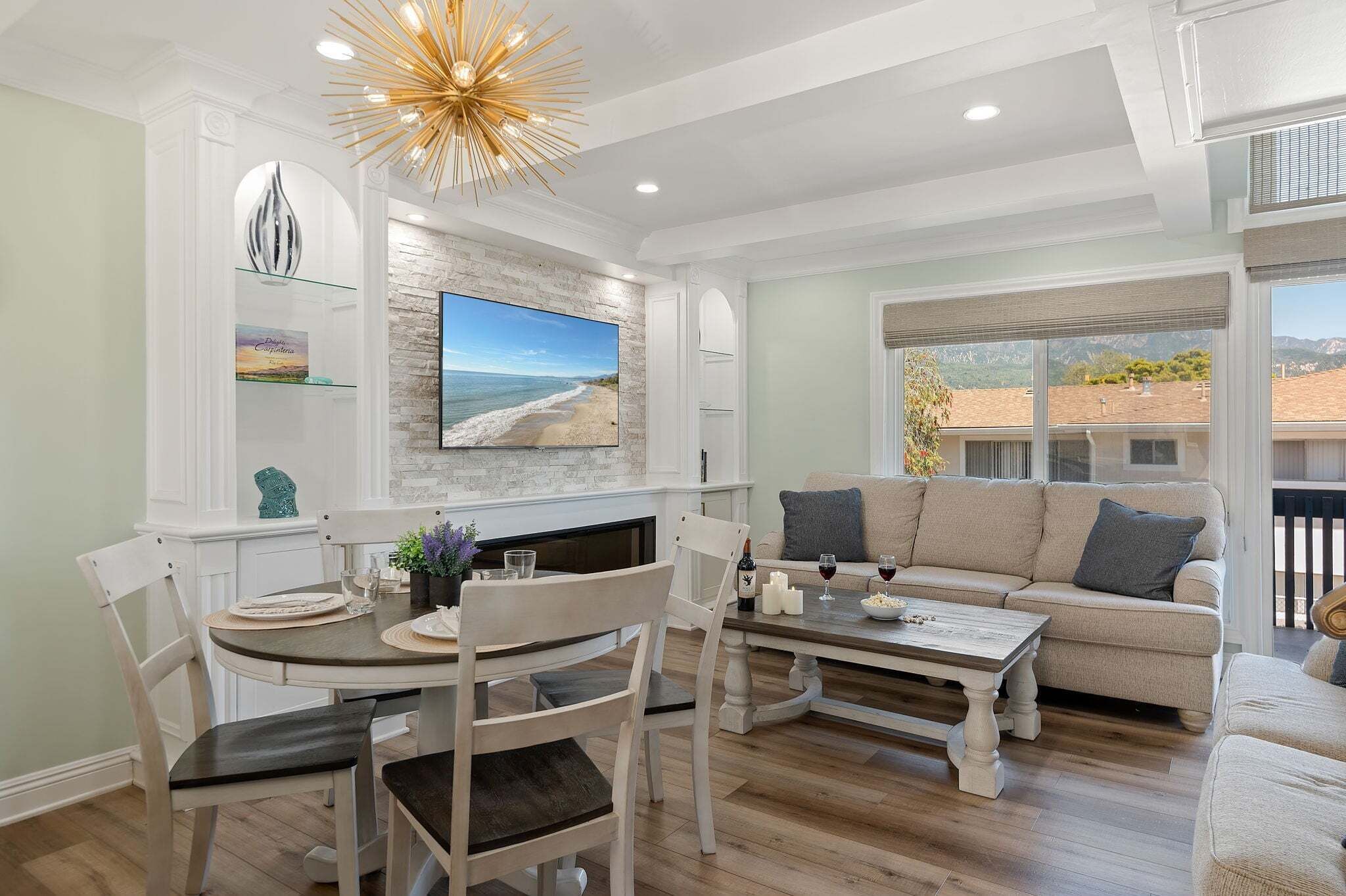 A modern living room with a TV, a sofa, a dining table, and a fireplace.