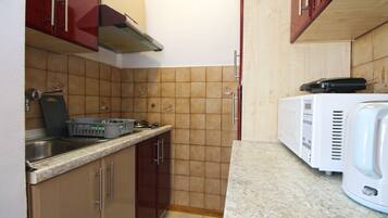 A compact kitchen with a stove, microwave, and a coffee maker on the counter.