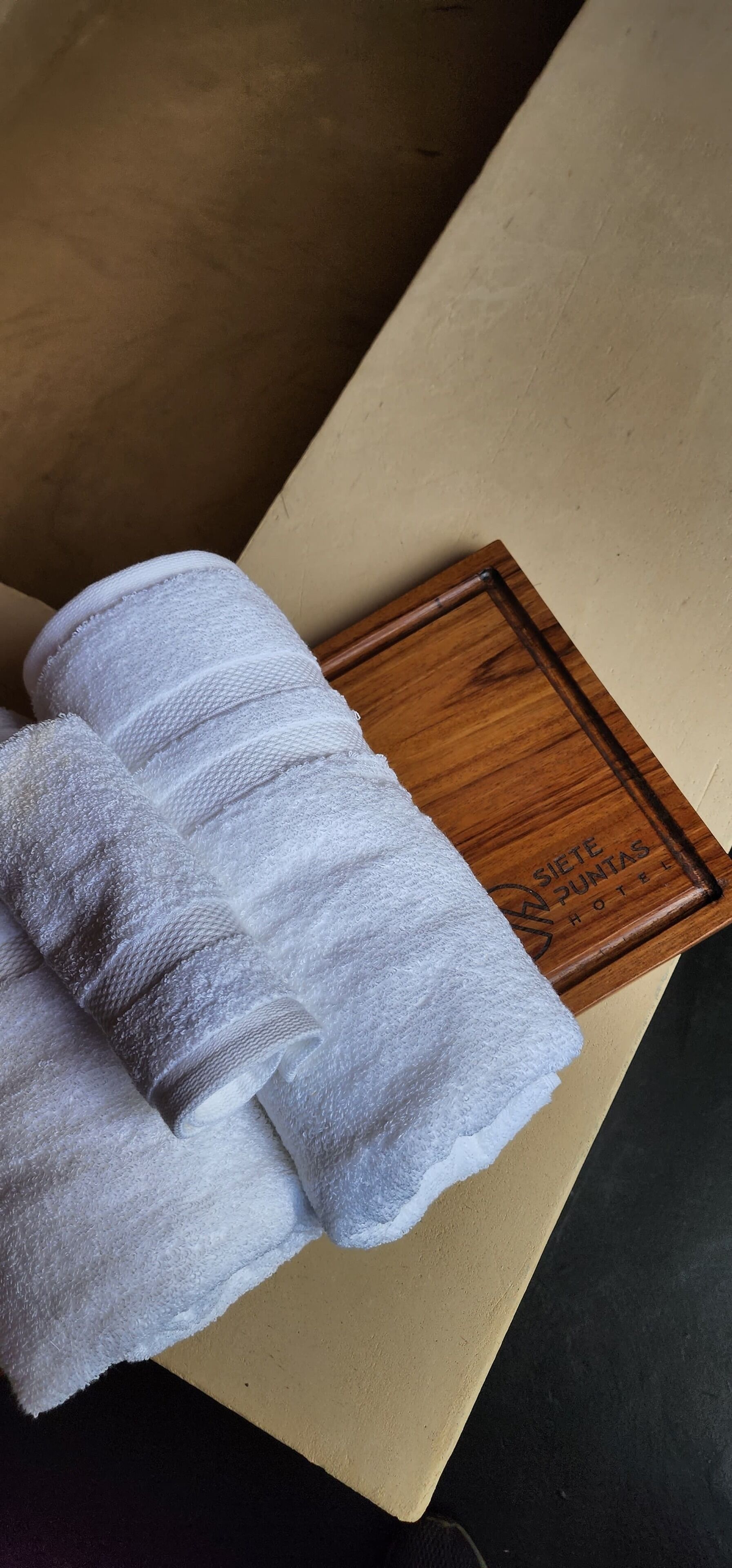 A white towel on a wooden tray with the text "Siete Puntas Hotel".