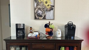 A kitchen counter with a coffee maker, a jar labeled "COFFEE," and a mug rack. - Cozy pet friendly house with a great outdoor space, and fully stocked kitchen.   (Las Cruces)