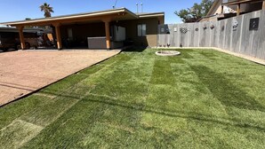 A residential backyard with a well-maintained lawn, a patio area, and a fenced yard. - Cozy pet friendly house with a great outdoor space, and fully stocked kitchen.   (Las Cruces)
