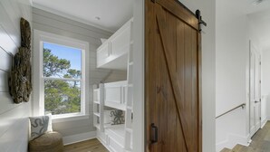 A room with a large window, built-in shelving, a wooden door, and a small seating area.