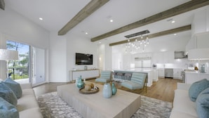 A spacious living area with a large sofa, a coffee table, and a dining area.