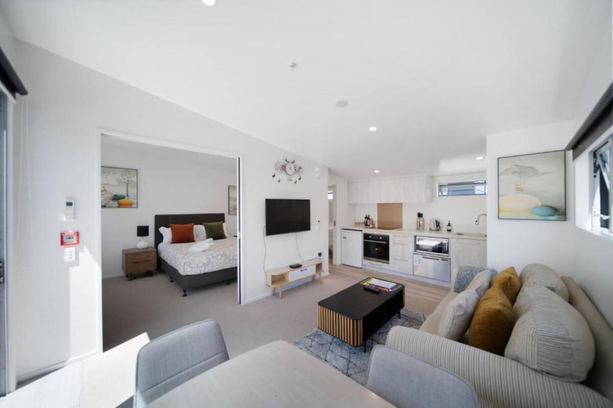 A modern, open-plan living space with a kitchen, dining area, and bedroom.
