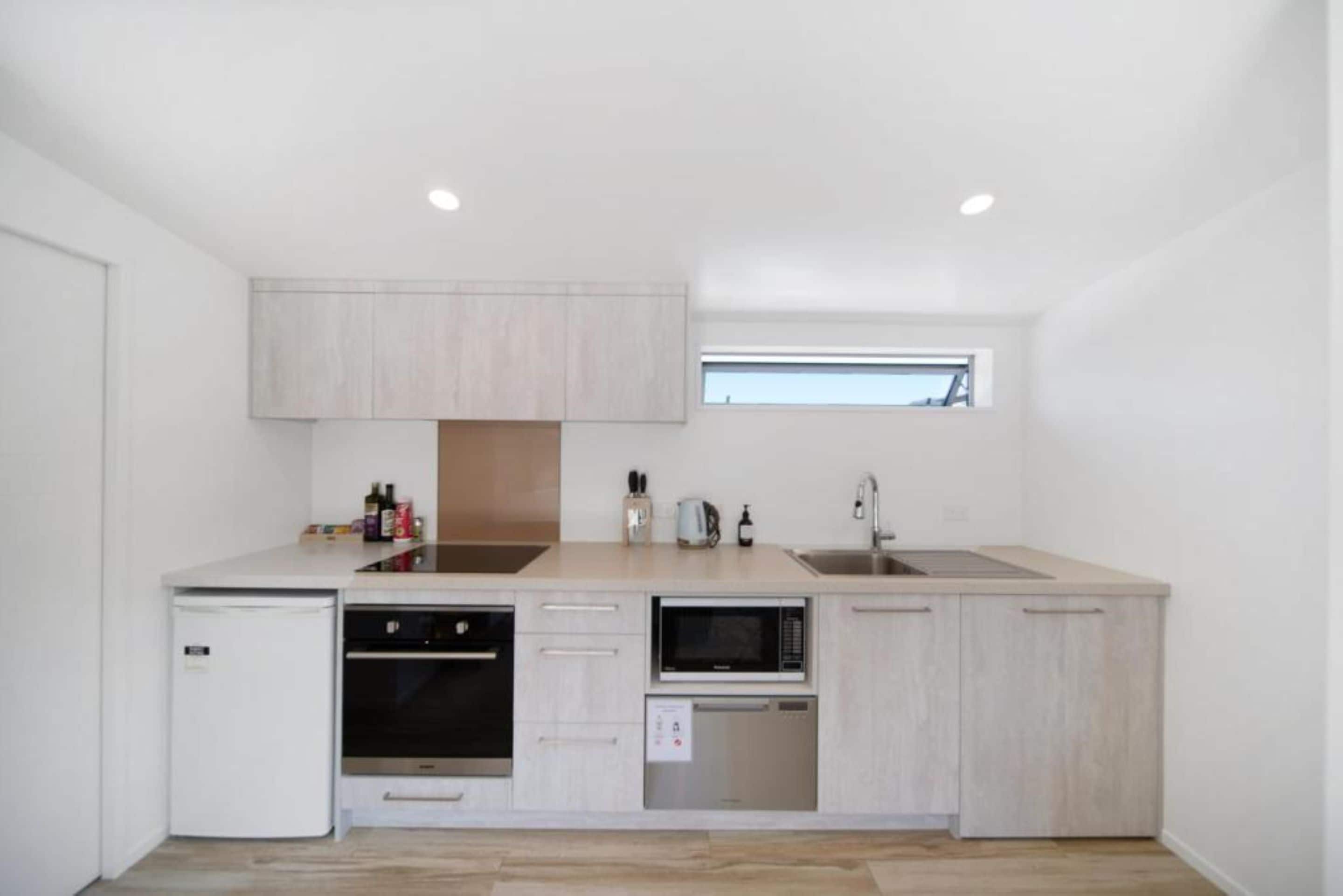 A compact kitchen with a refrigerator, oven, microwave, and sink.
