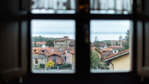 A view through a window with a view of a residential area with houses and a body of water in the distance. - Poo de Llanes House close to the Beach - El Balandro (Poo De Llanes)