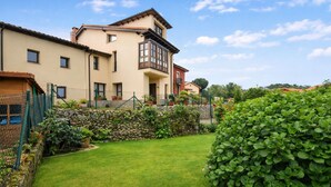A two-story house with a stone wall and a well-maintained garden. - Poo de Llanes House close to the Beach - El Balandro (Poo De Llanes)