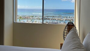 Camera d'albergo con un'ampia finestra che si affaccia su un porto turistico e il mare.