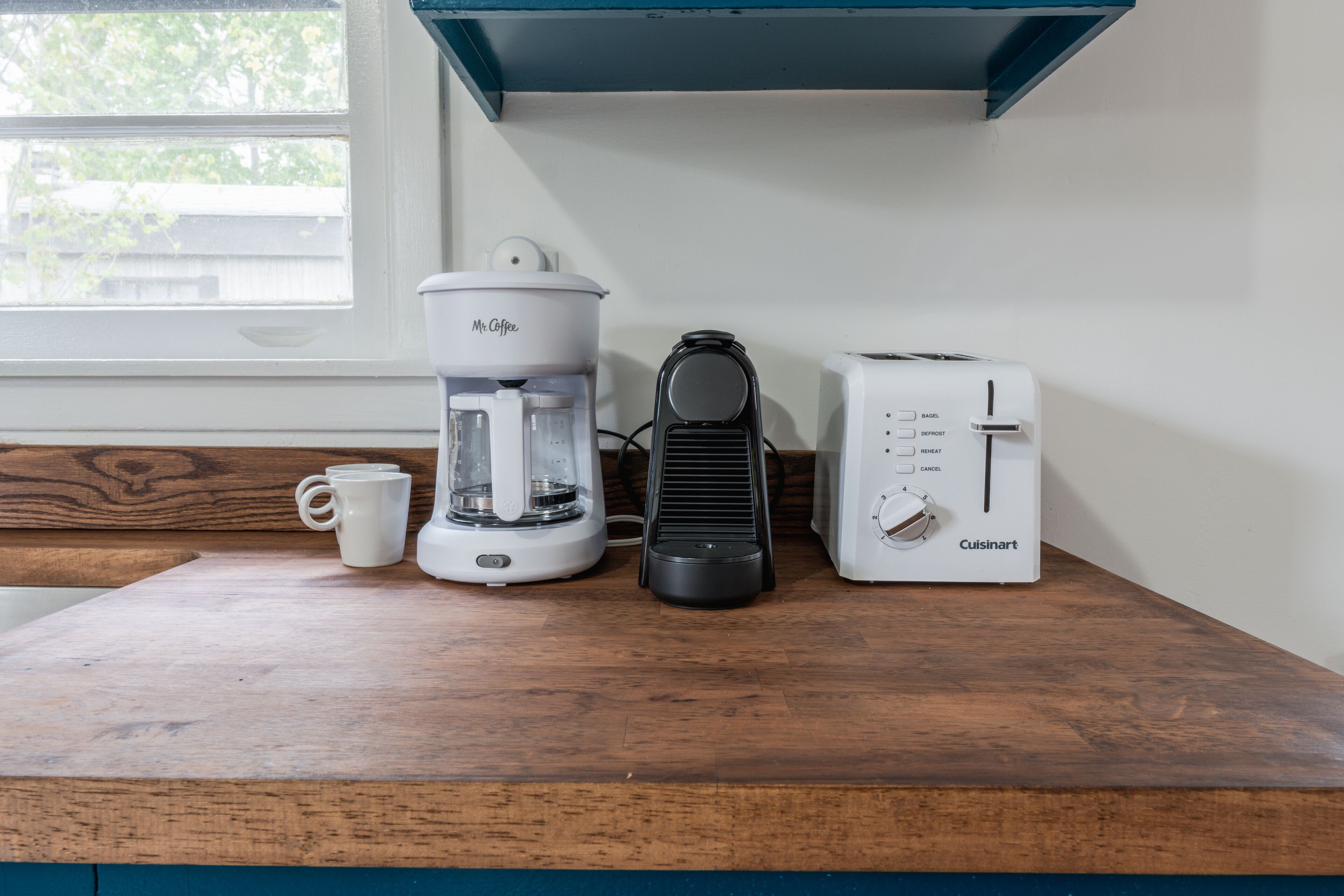 A kitchen counter with a coffee maker, a toaster, and a mug.