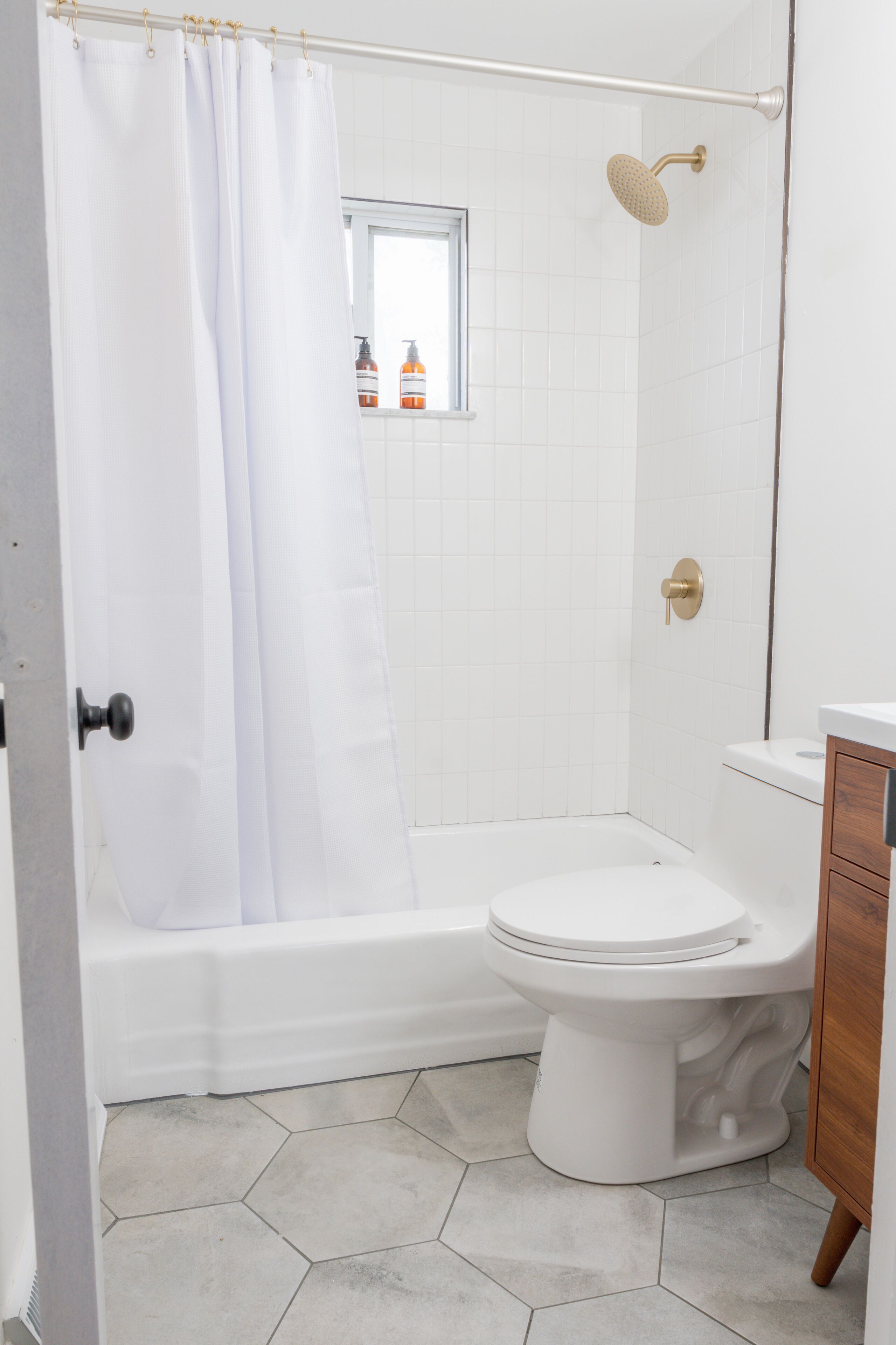 A bathroom with a shower, toilet, and a window.