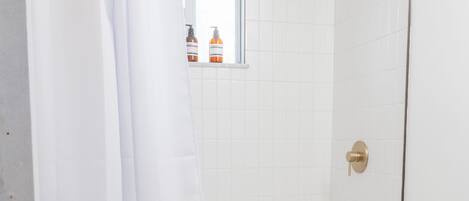 A bathroom with a shower, toilet, and a window.