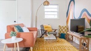 Een woonkamer met een bank, fauteuil, salontafel en een televisie.