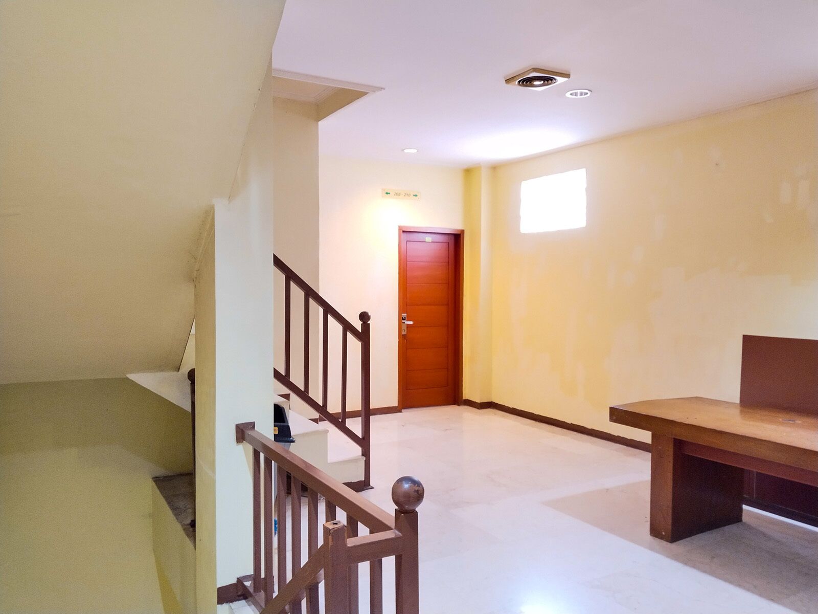 A room with a wooden staircase, a door, and a bench.