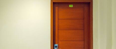 A wooden door with a number plate indicating room 310, a doorbell, and a sign above showing room numbers 308-310.