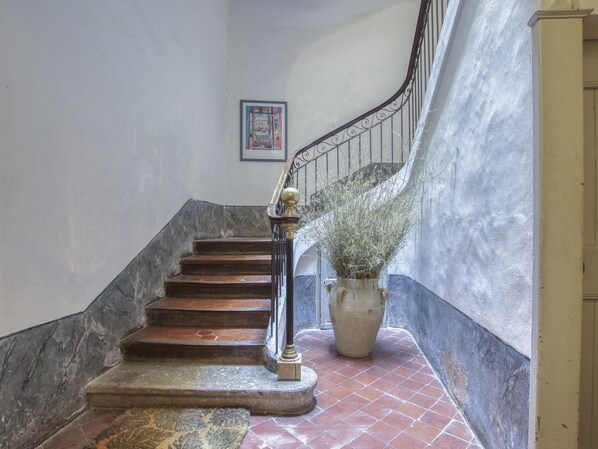 A staircase with a metal railing, a potted plant, and a framed picture on the wall.