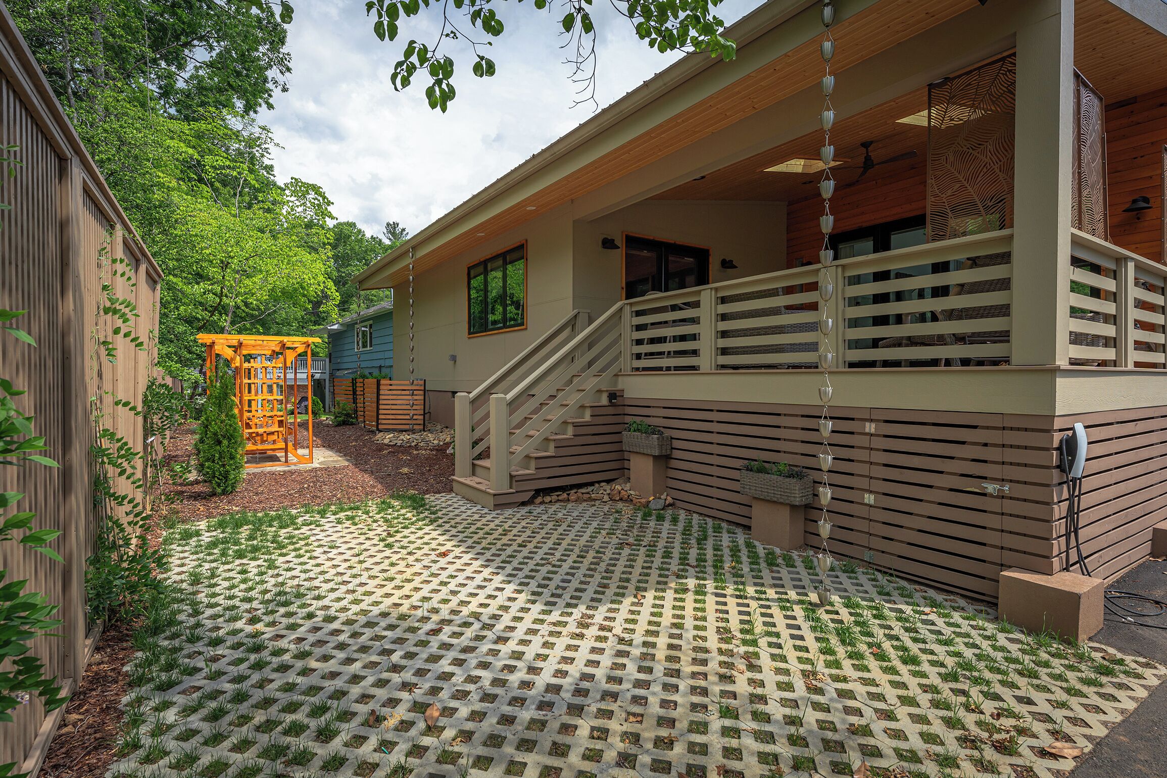 A modern house with a wooden deck, a staircase, and a covered porch.