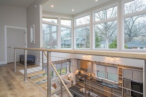 A spacious kitchen with large windows, a staircase, and modern appliances.