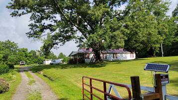 A rural property with a white building, a gravel path, and a solar panel.
