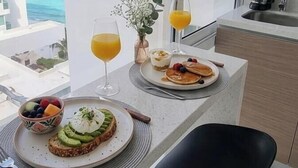 Un balcone con colazione allestita, inclusi toast, frutta e succo, con vista sulla costa.