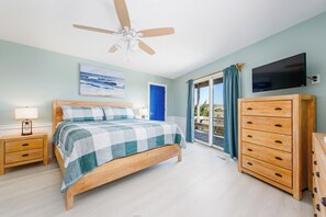 A bedroom with a bed, wooden nightstands, a TV, and a ceiling fan. - OBX Pool Beachfront Hot Tub 5Bed Volleyball Arcade (Waves)