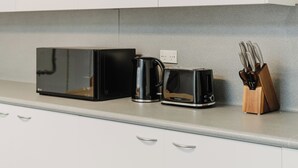 Een keukenblad met een magnetron, koffiezetapparaat, broodrooster en een messenblok.