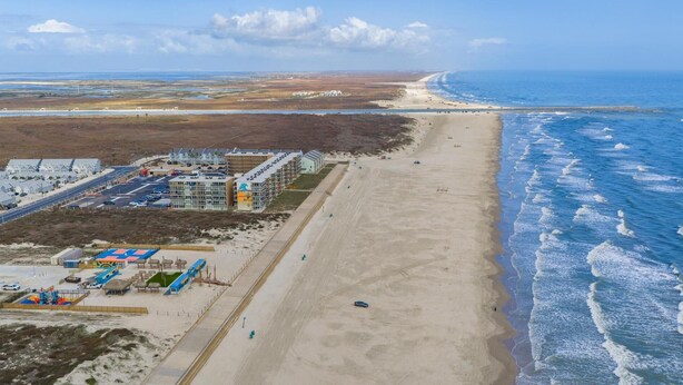 A coastal hotel with multiple buildings, a beach, and a road leading to the beach. - Walk to the Beach- Peaceful and Modern Condo (Corpus Christi)