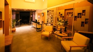 A warmly lit interior with a reception desk, seating area, and shelves with decorative items. - Krem Marin Suits Otel (Cesme)