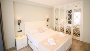 A neatly arranged bedroom with a large bed, bedside tables, and a wardrobe with a glass door. - Krem Marin Suits Otel (Cesme)