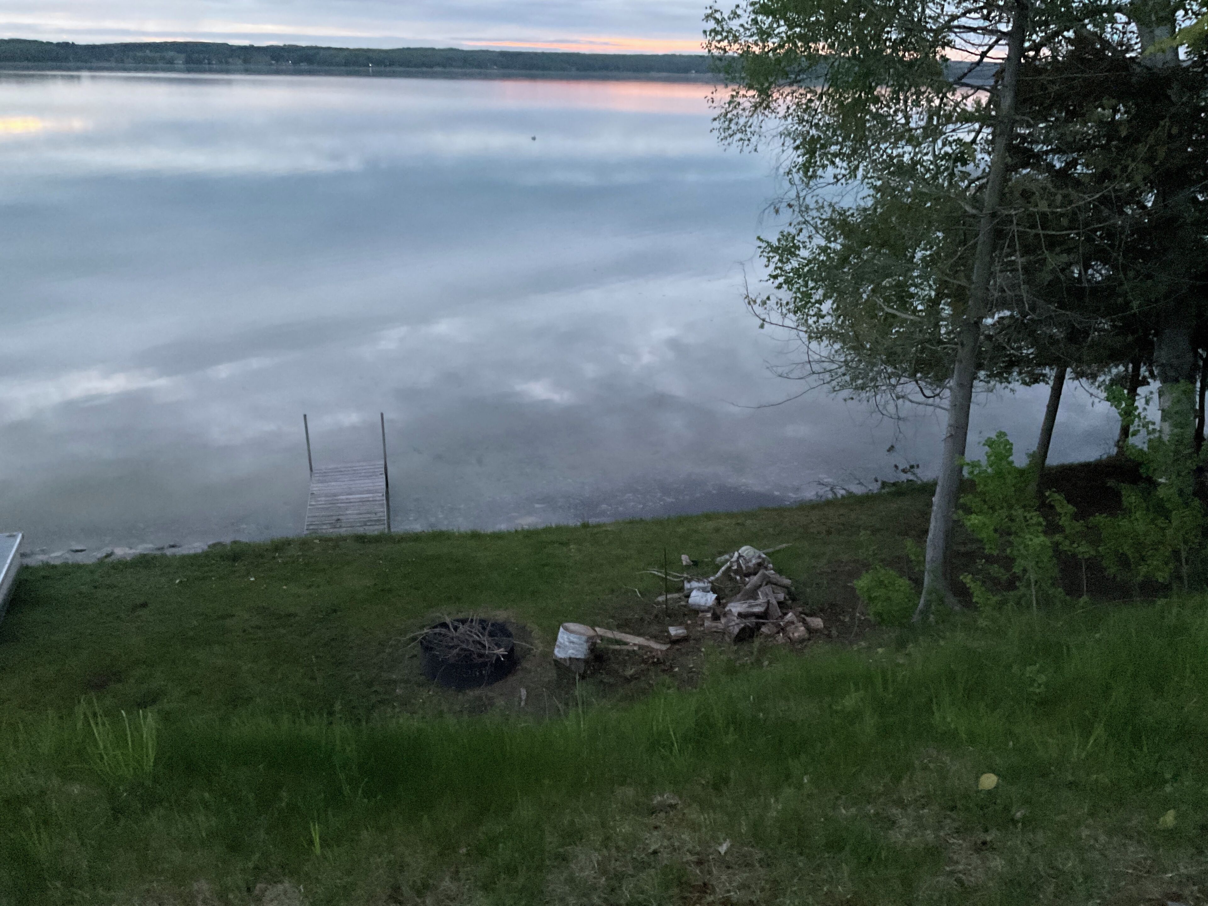 Blick auf einen See mit Steg, Rasenfläche und Bäumen.
