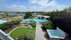 A backyard with a swimming pool, hot tub, and a patio area.