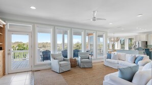 A spacious living room with a large window, a ceiling fan, and a view of the outdoors.