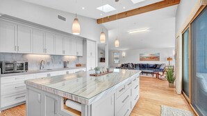 Een moderne keuken met een groot eiland, witte kasten en hanglampen.