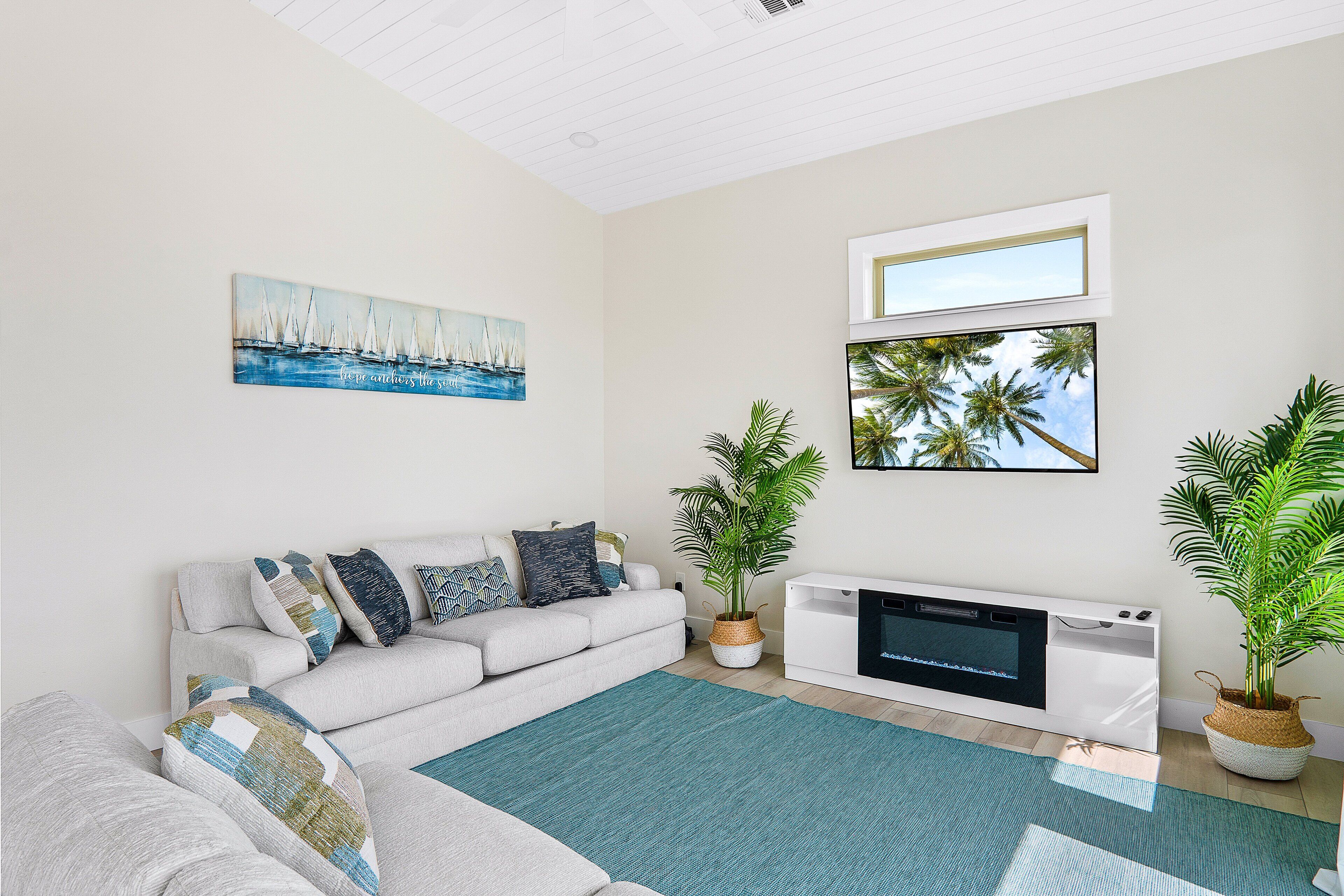 A living room with a white sofa, teal rug, and a fireplace.