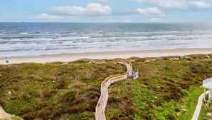 Een kustpad dat naar een strand leidt, met een houten looppad en een uitkijkplatform.
