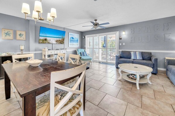 A spacious living area with a dining table, a sofa, and a ceiling fan.