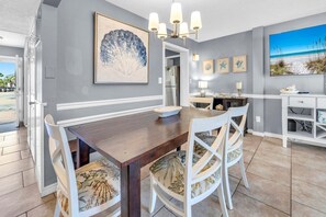 A dining area with a wooden table, white chairs, a chandelier, and artwork on the walls.