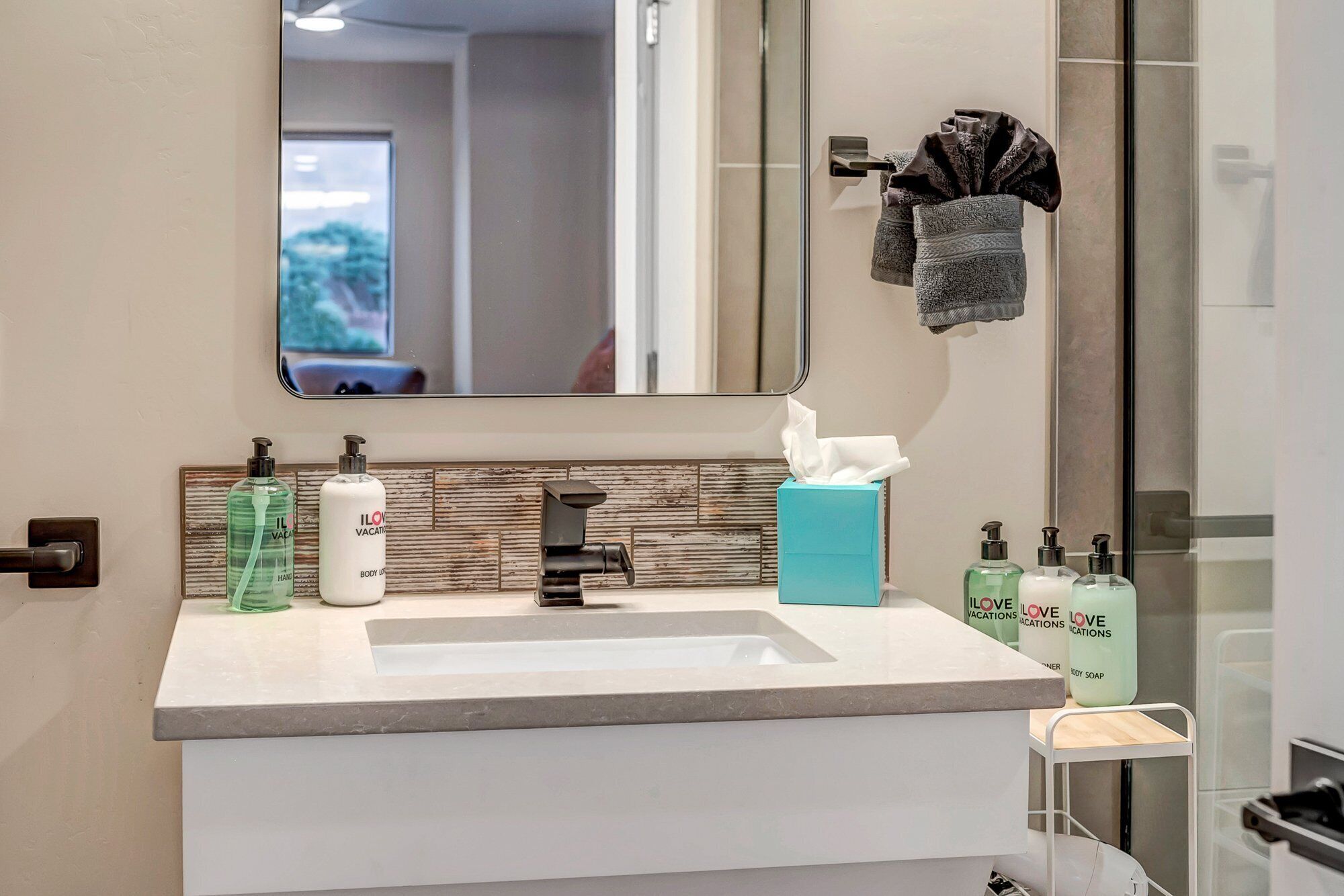 Une salle de bain moderne avec un grand miroir, un lavabo et des articles de toilette.