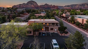 A residential area with a prominent building featuring a brick facade, a parking lot, and a mountainous backdrop.