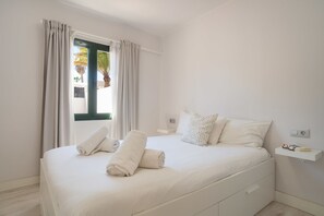 Relax in a serene bedroom with a large bed, neatly folded towels, and a reading nook.