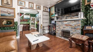 Un salon chaleureux avec une cheminée, un plancher en bois et un téléviseur fixé au mur.
