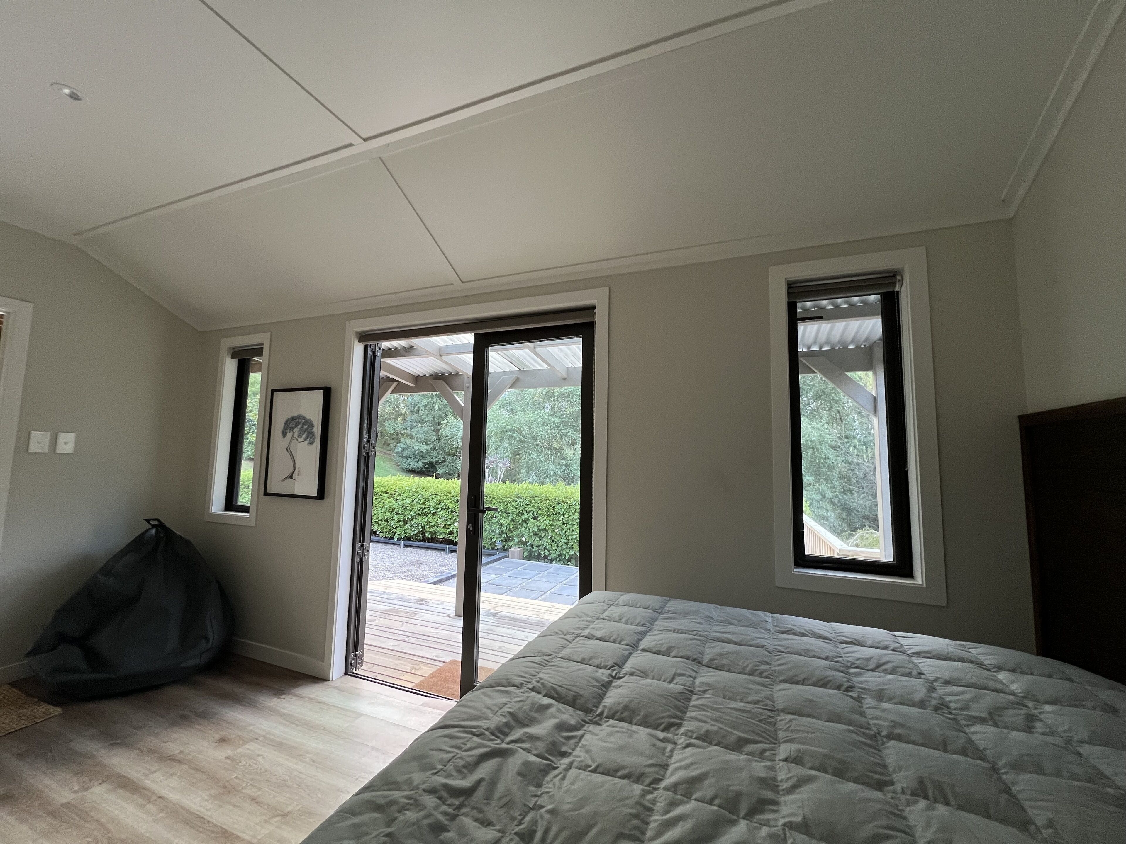 Een slaapkamer met een bed, een schuifdeur naar een terras en een klein raam.