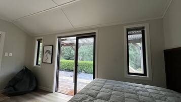 Een slaapkamer met een bed, een schuifdeur naar een terras en een klein raam.