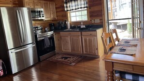 A wooden cabin kitchen with a refrigerator, stove, microwave, and wooden cabinets. - Boo Boo's Cabin - Charming Lake Front Cabin located 5 miles to Helen, GA!  (Cleveland)