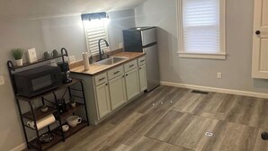 A compact kitchen with a microwave, coffee maker, and a small sink.