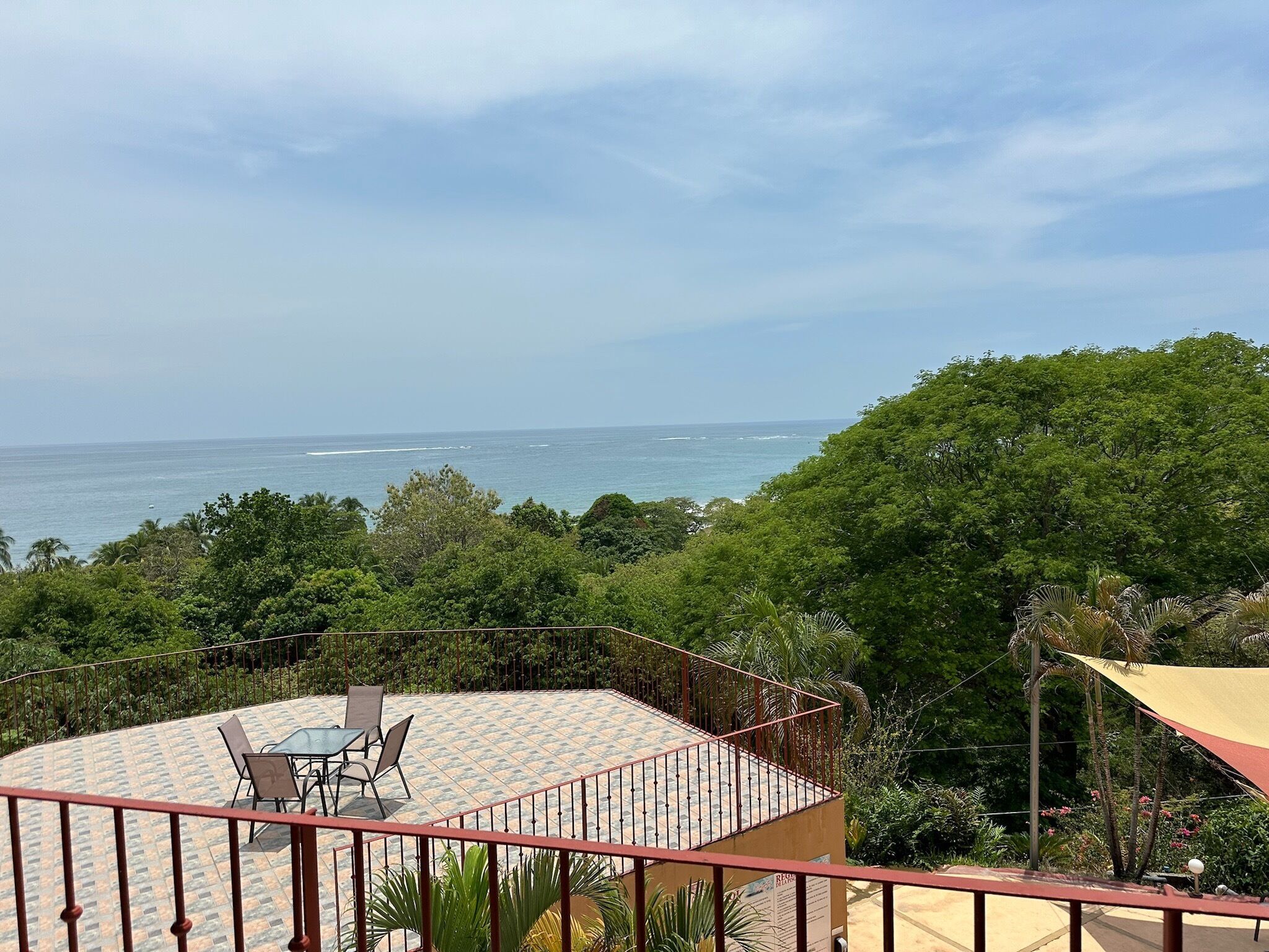 Una terraza con vistas al océano, rodeada de abundante vegetación.
