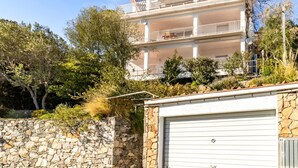 A multi-story building with balconies, a stone wall, and a garage. - Cap Ras 04.3 - Apartment with terrace and sea view (Llança)