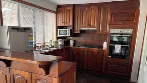 Una cocina con gabinetes de madera, un refrigerador de acero inoxidable, un microondas, una estufa y un horno.