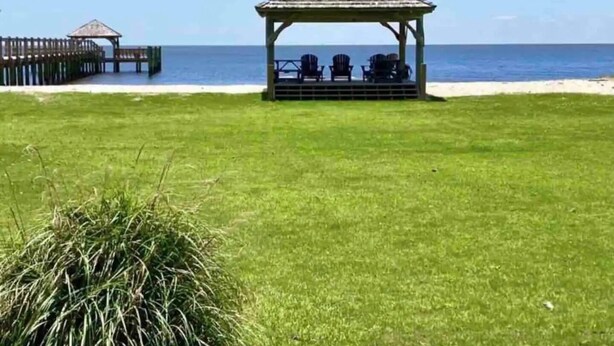 Een prieel met buitenzitplaatsen, een houten terras en uitzicht op zee.