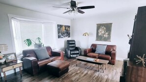 A living room with a wooden floor, two leather sofas, a coffee table, a black leather chair, and a ceiling fan. - Pikes Peak Panorama View (Colorado Springs)