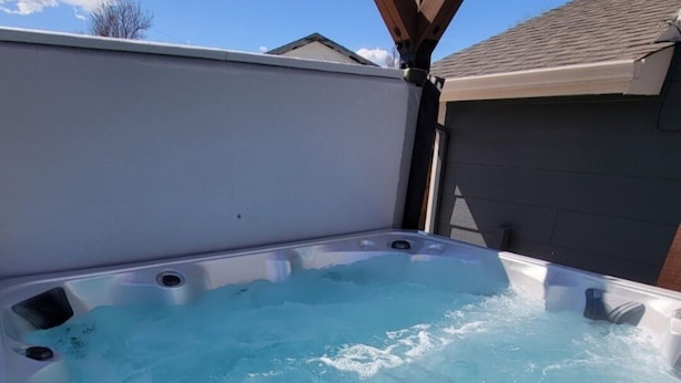 A hot tub with multiple jets, surrounded by a wooden deck and a house in the background. - Pikes Peak Panorama View (Colorado Springs)